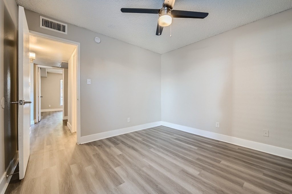 A room with a ceiling fan and wooden flooring.