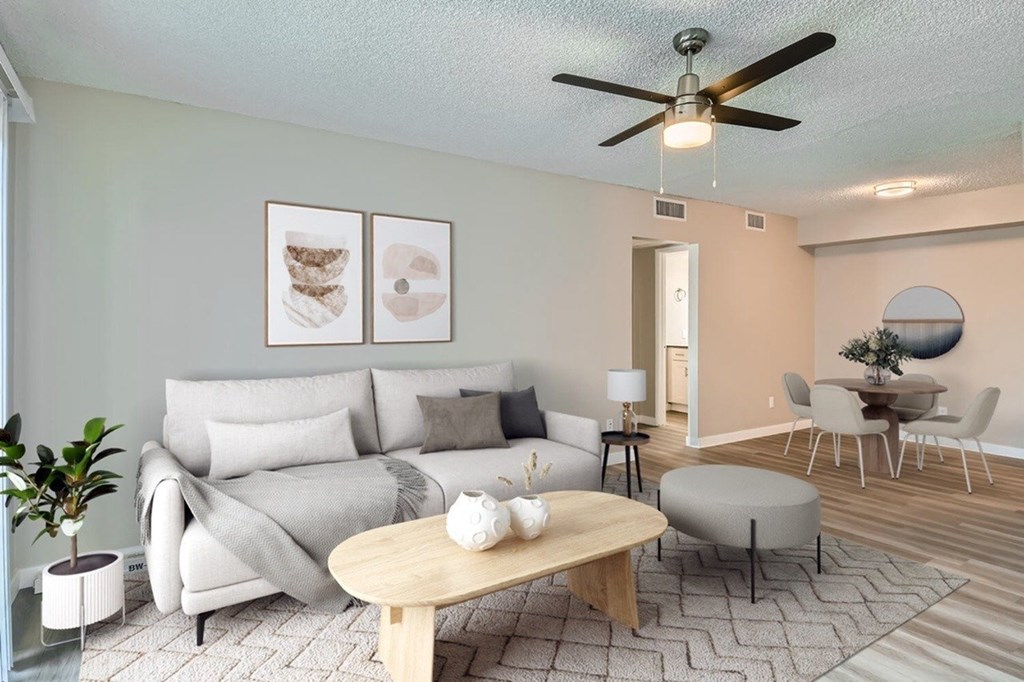 A living room with a grey couch, a wooden coffee table, and a ceiling fan.