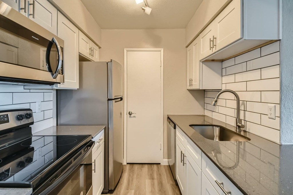 A kitchen with a black stove top oven and a white refrigerator.