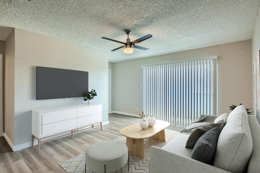 A living room with a grey couch, a white cabinet, a wooden coffee table, and a ceiling fan.