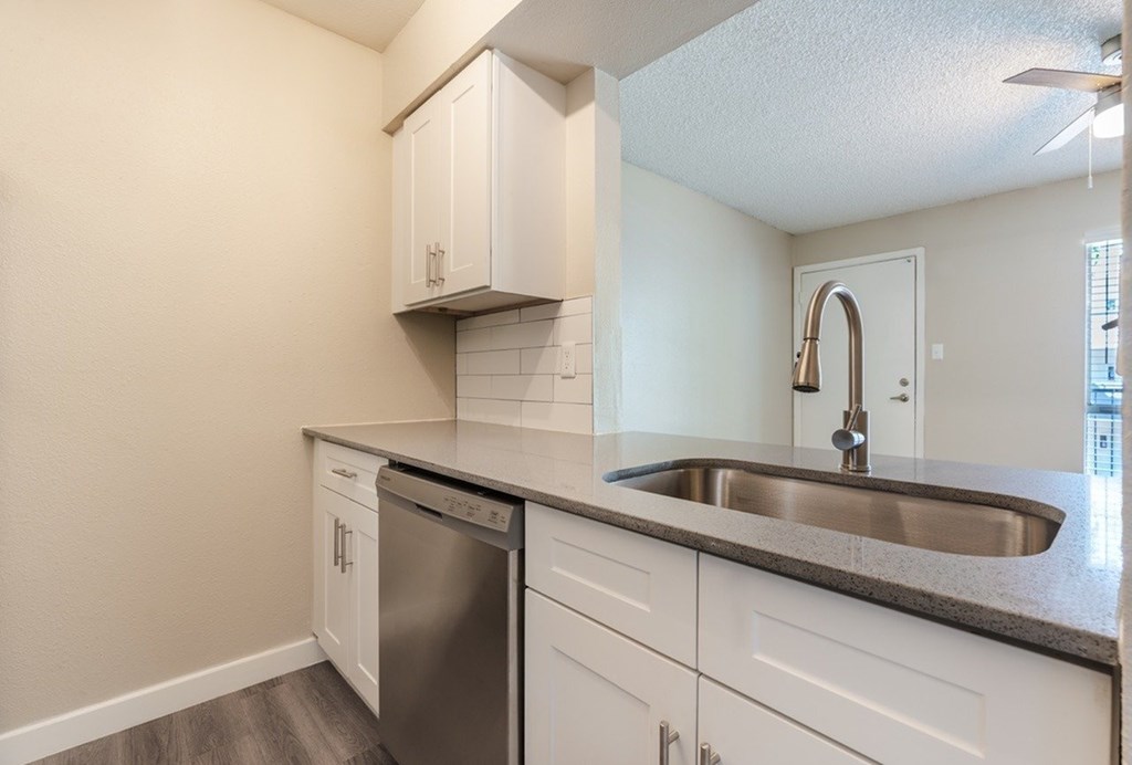 A kitchen with a stainless steel dishwasher and a sink.