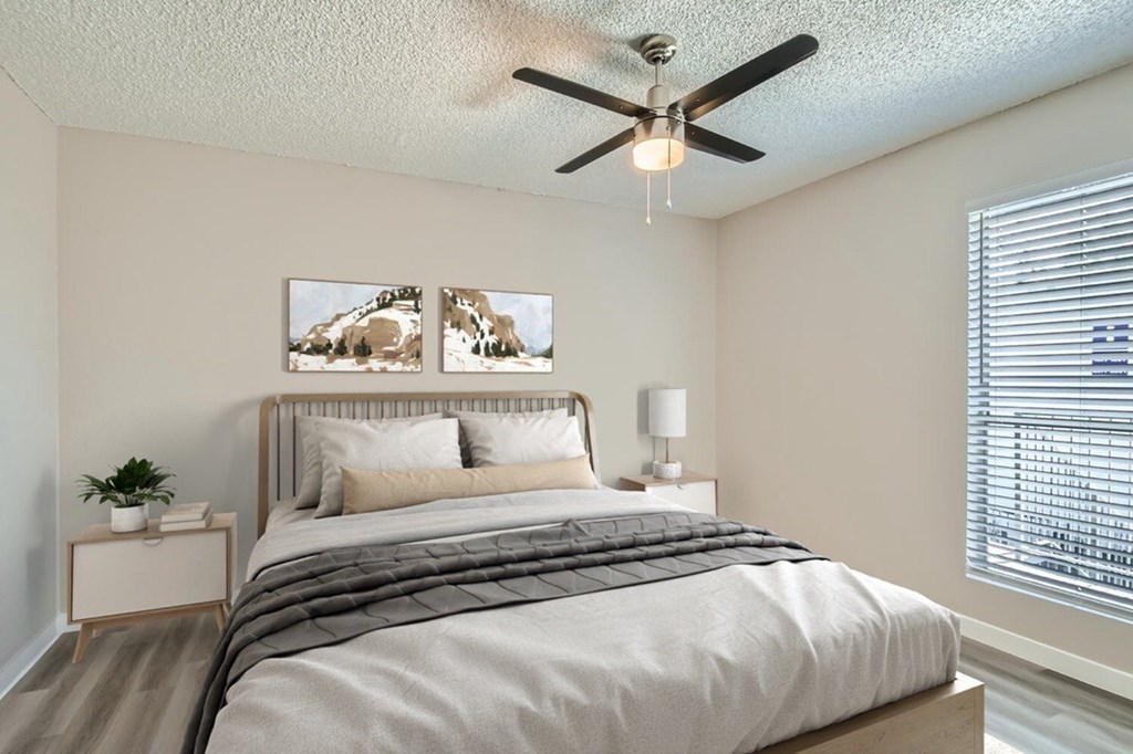 A bedroom with a bed, nightstand, and a ceiling fan.