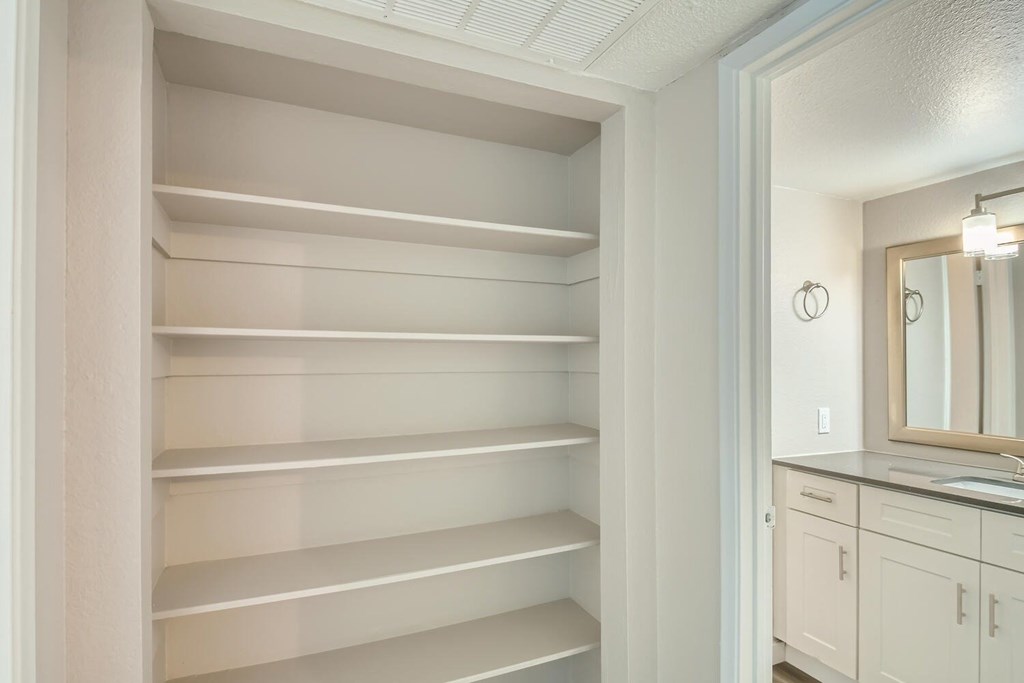 A white bathroom with a large mirror and a vanity.