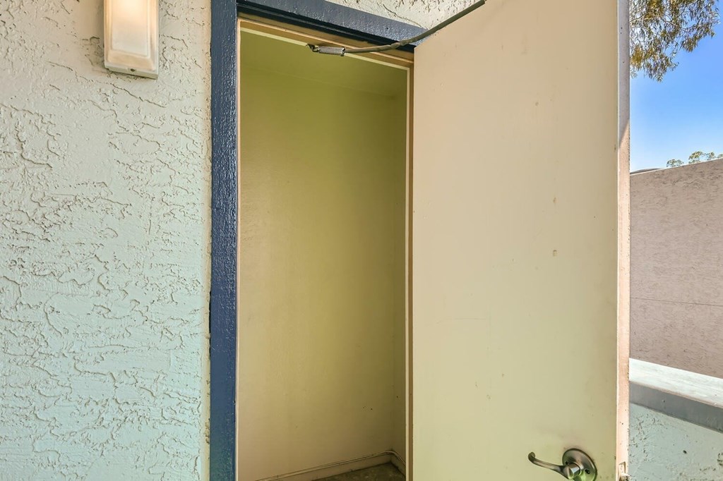 A door with a handle is open to a room with a white wall.