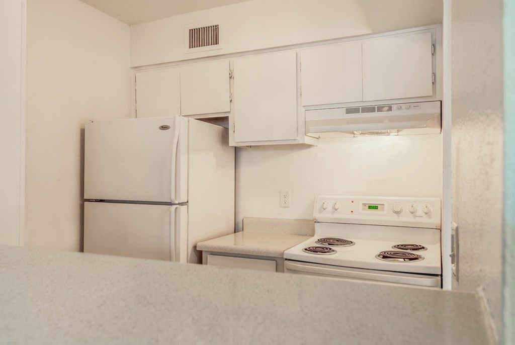 A white kitchen with a refrigerator, oven, and microwave.