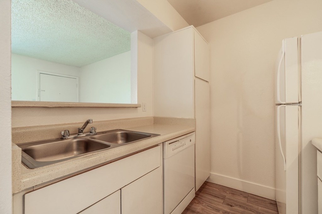 A kitchen with white cabinets and a stainless steel sink.