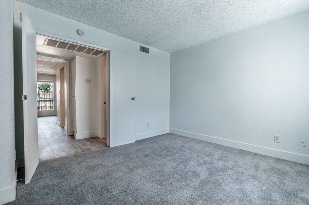 A spacious room with a carpeted floor and white walls.