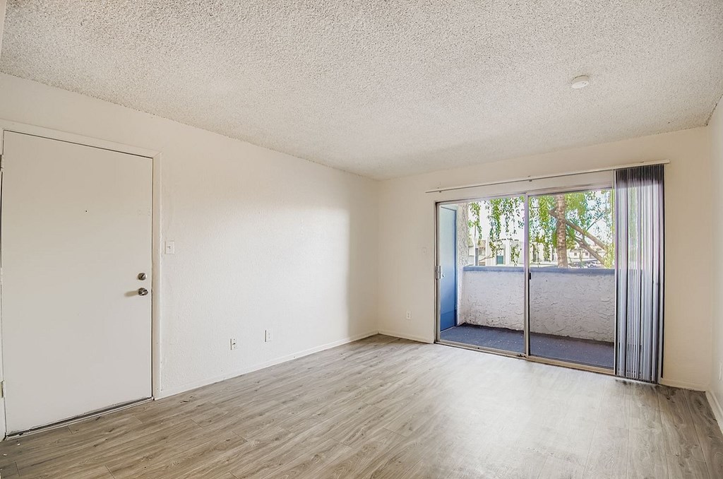 A room with a sliding glass door leading to a balcony.