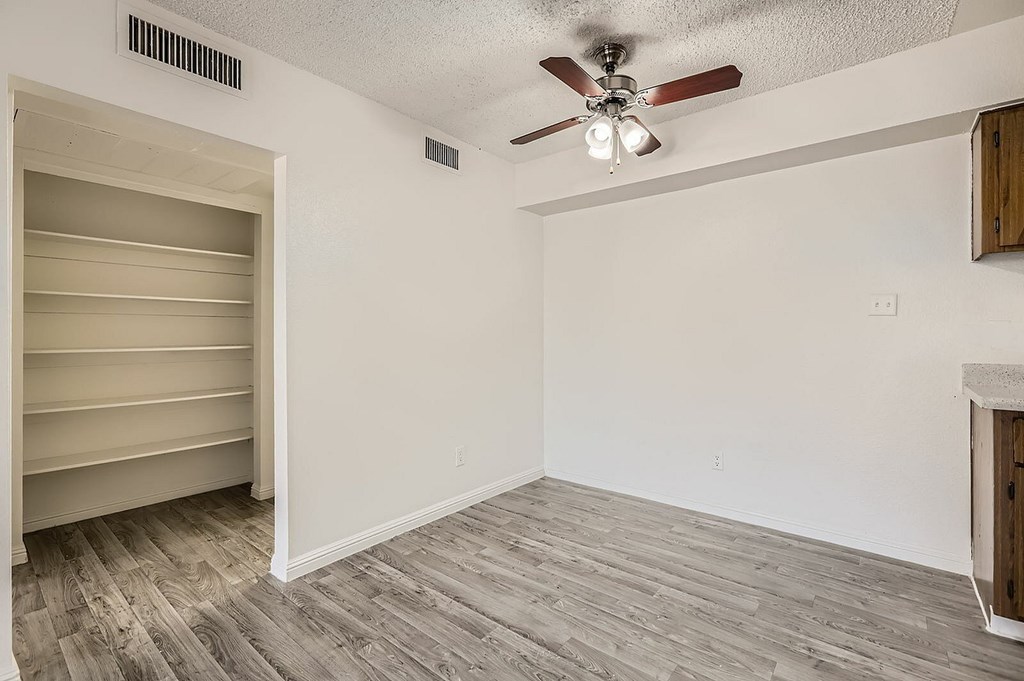 A room with a ceiling fan and a shelving unit.