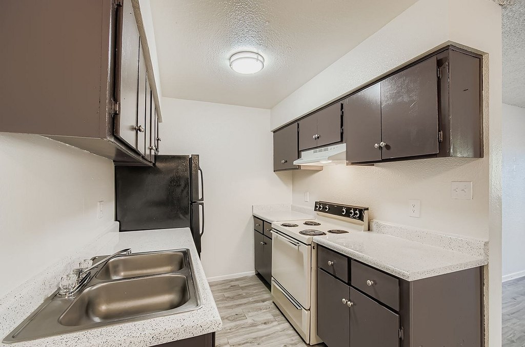 A kitchen with a white fridge, wooden cabinets, and a ceiling fan.