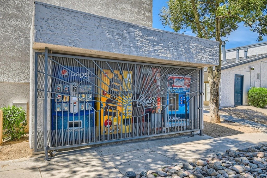 A Pepsi vending machine is behind a metal gate.