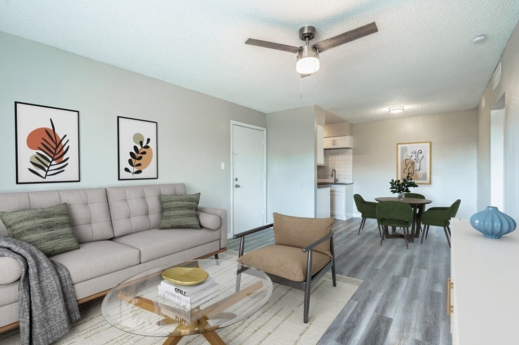A living room with a grey couch, a coffee table, and a ceiling fan.