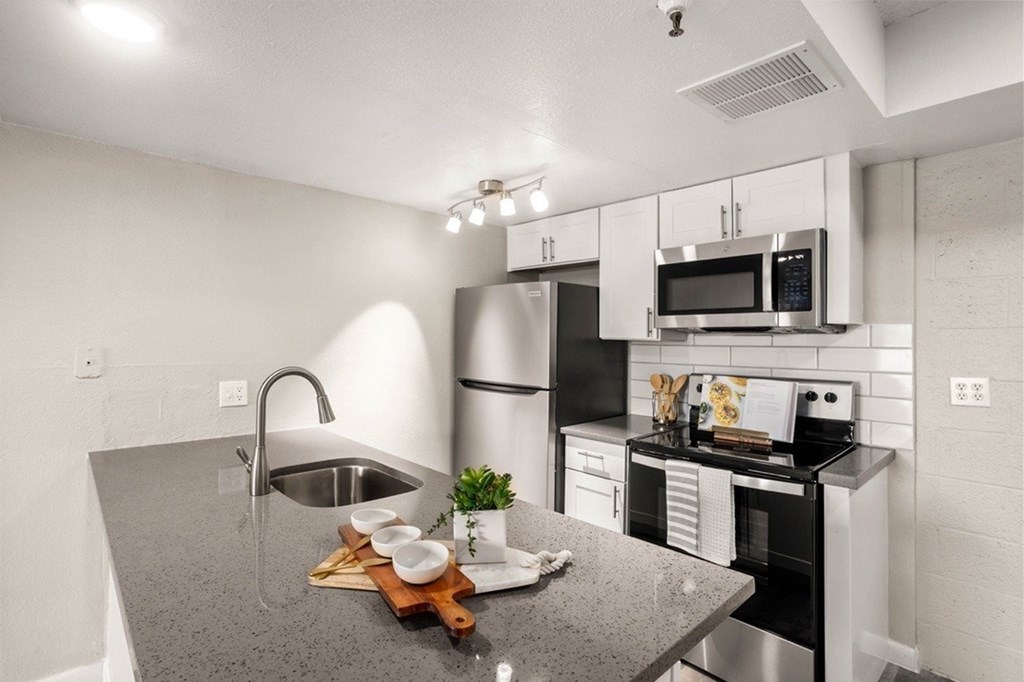 A kitchen with a grey counter top and stainless steel appliances.
