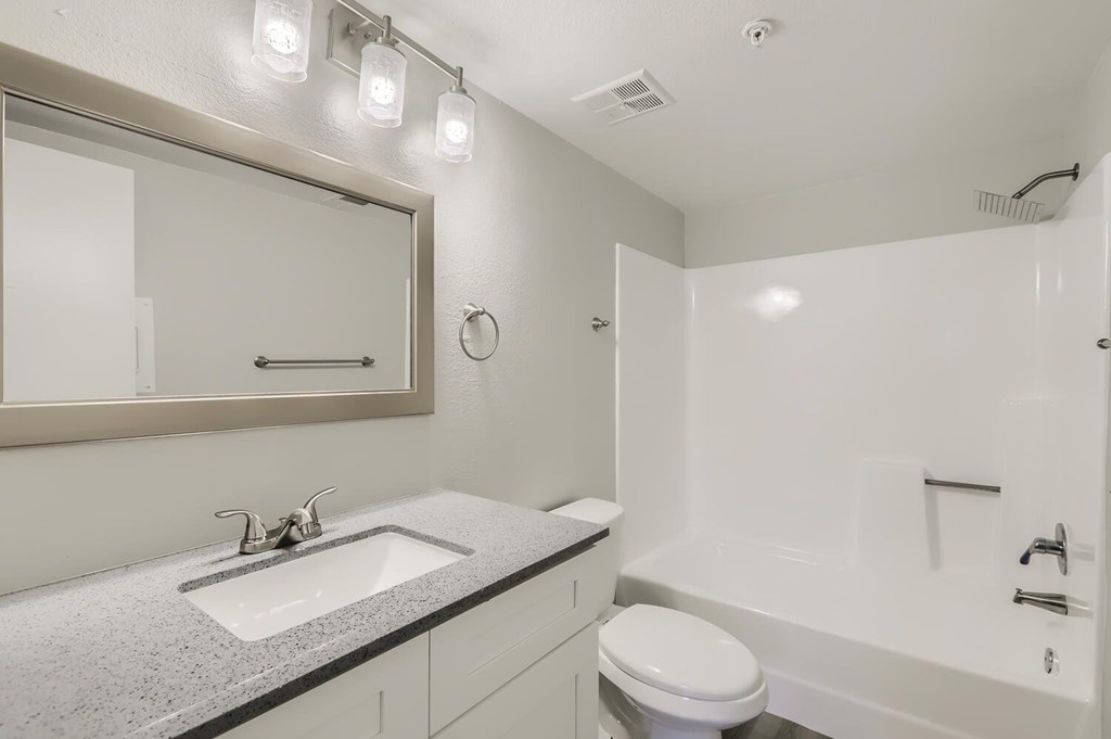 A modern bathroom with a white toilet, sink, and bathtub.