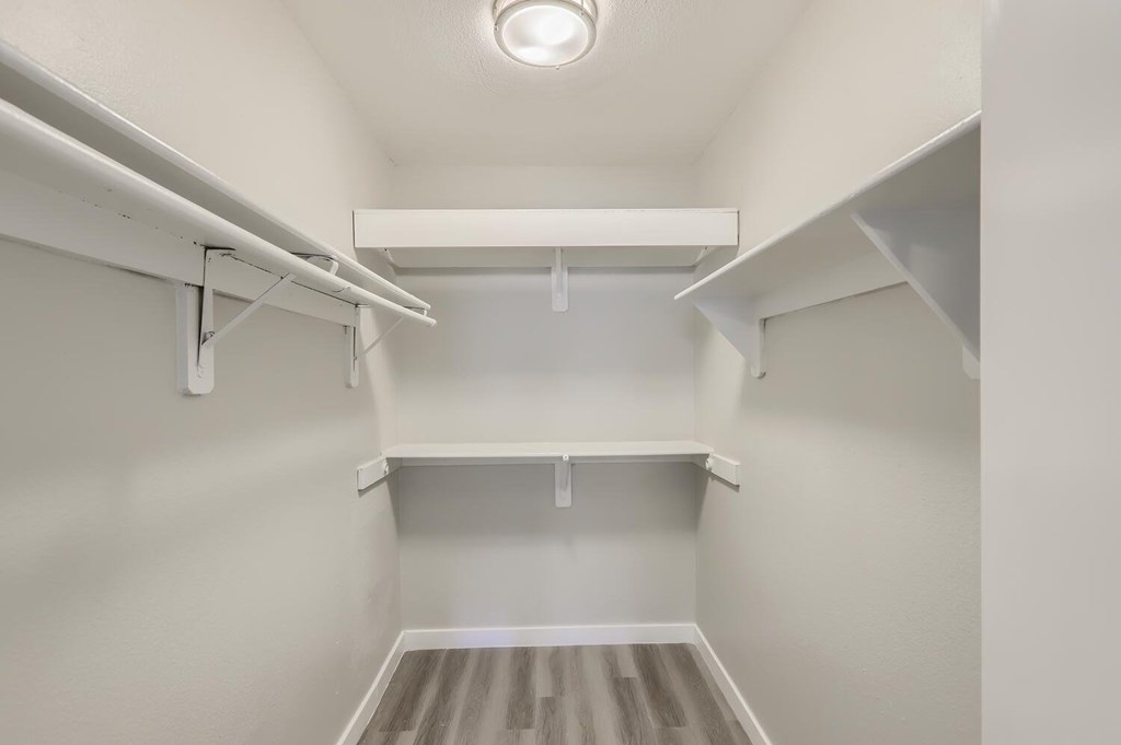 A white walk-in closet with shelves and a light on the ceiling.