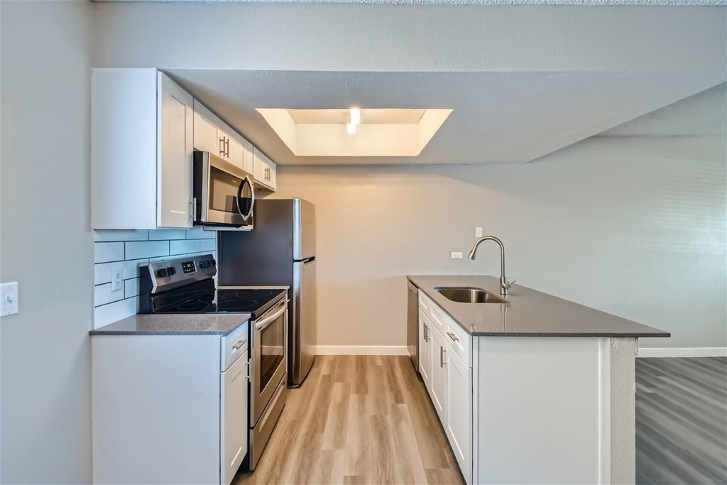 A kitchen with white cabinets and a black countertop.