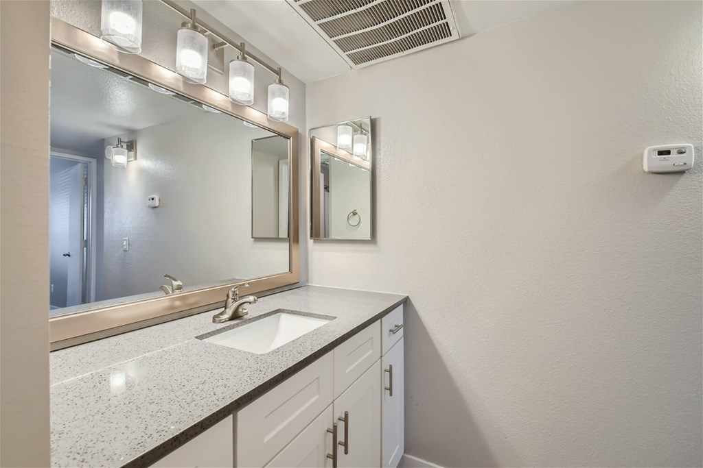 A bathroom with a sink, mirror, and lights.