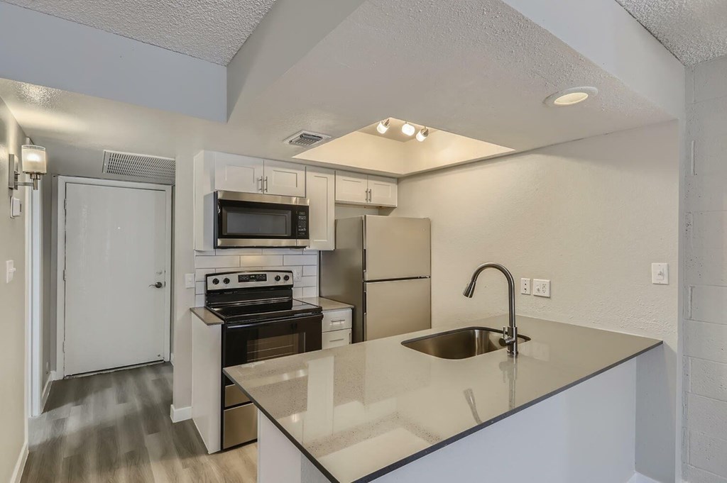 A kitchen with a sink, stove, and refrigerator.