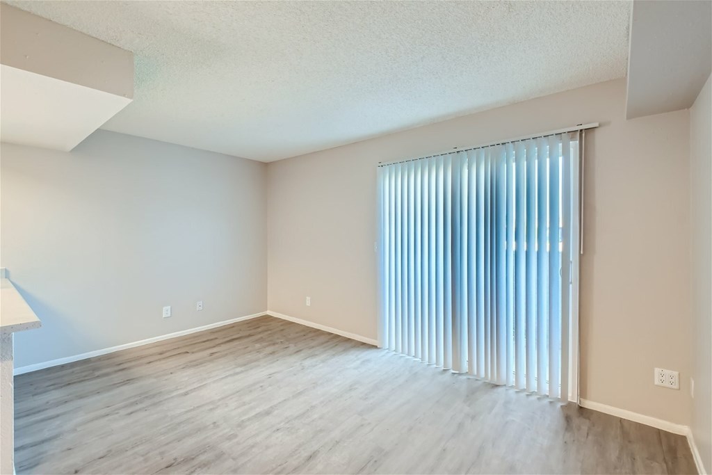 A room with a window covered by vertical blinds.