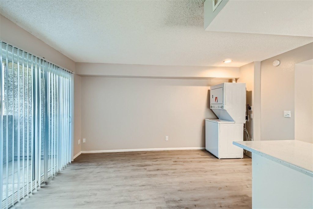 A room with a white refrigerator and a window with blinds.