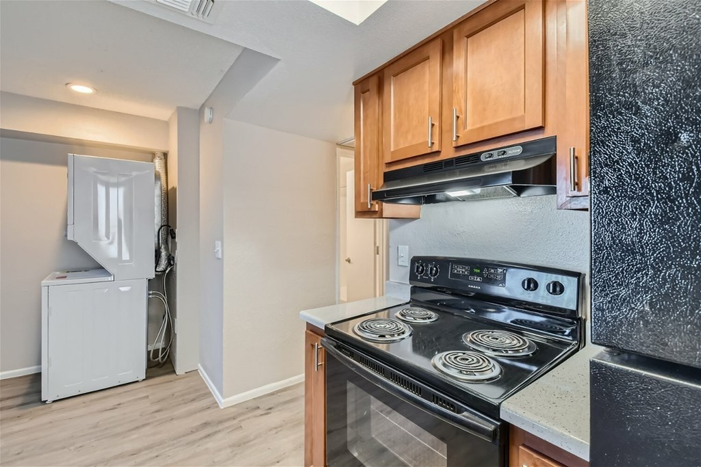 A kitchen with a stove top oven and a refrigerator.