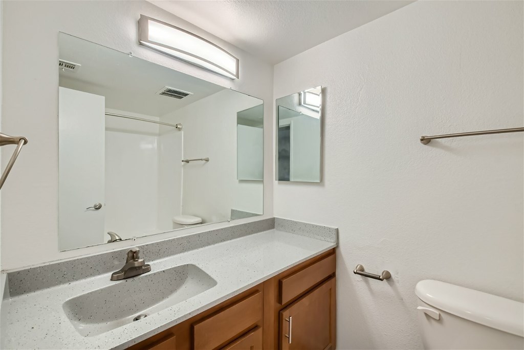A bathroom with a sink, mirror, and bathtub.