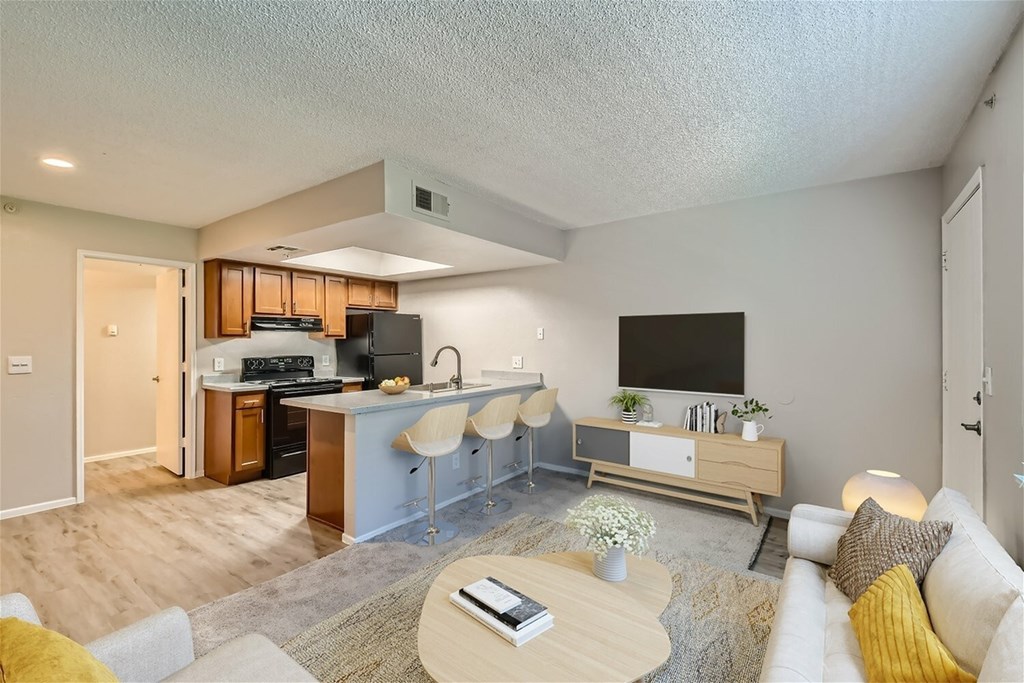 A modern living room with a kitchen area in the background.