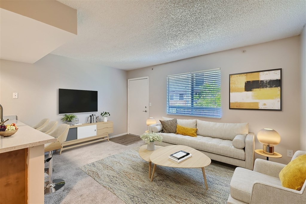 A living room with a white couch, a coffee table, and a flat screen TV.
