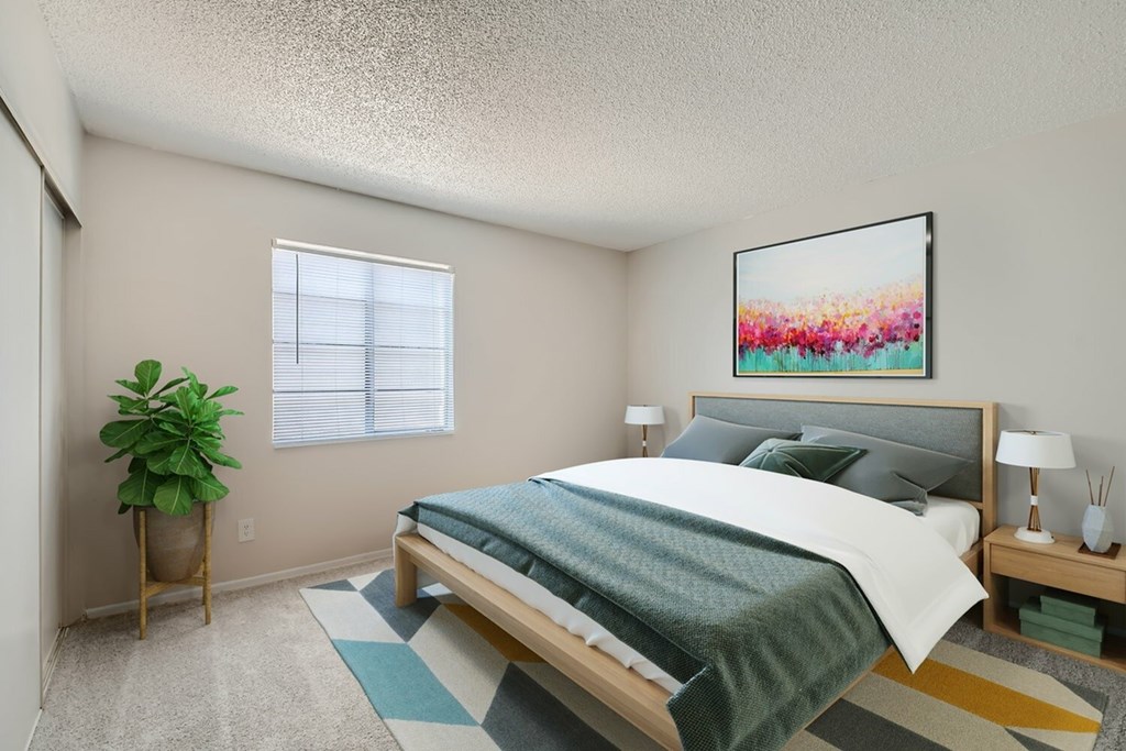 A bedroom with a bed, a potted plant, and a painting on the wall.