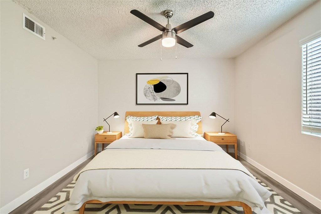 A bedroom with a bed, two lamps, and a ceiling fan.