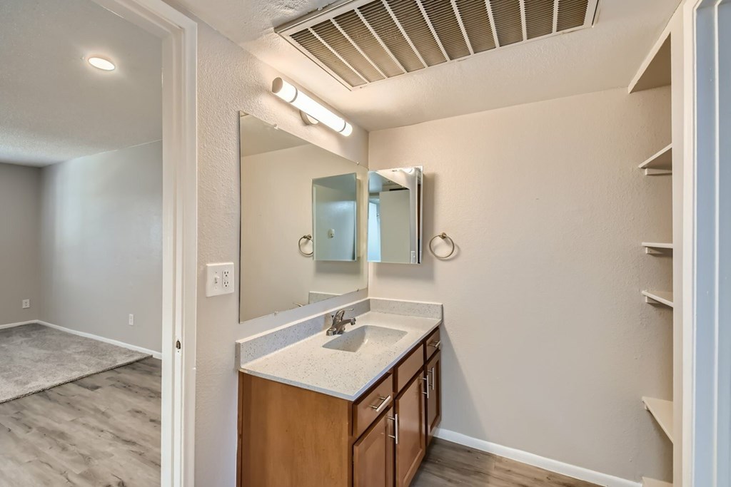 A bathroom with a sink, mirror, and lighting fixtures.