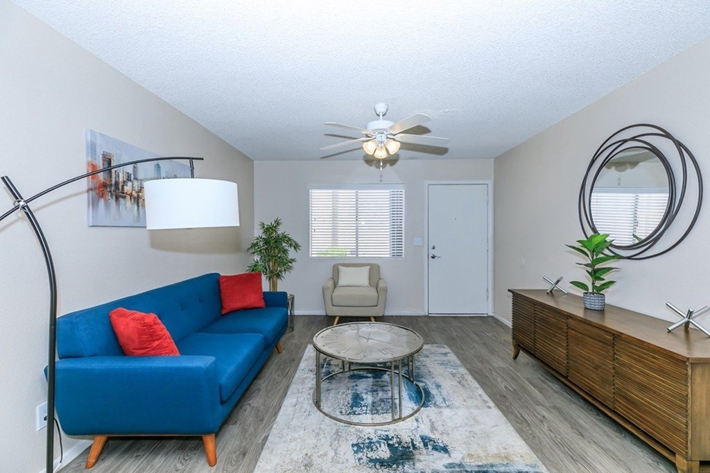 A blue couch sits in a living room with a ceiling fan and a rug.