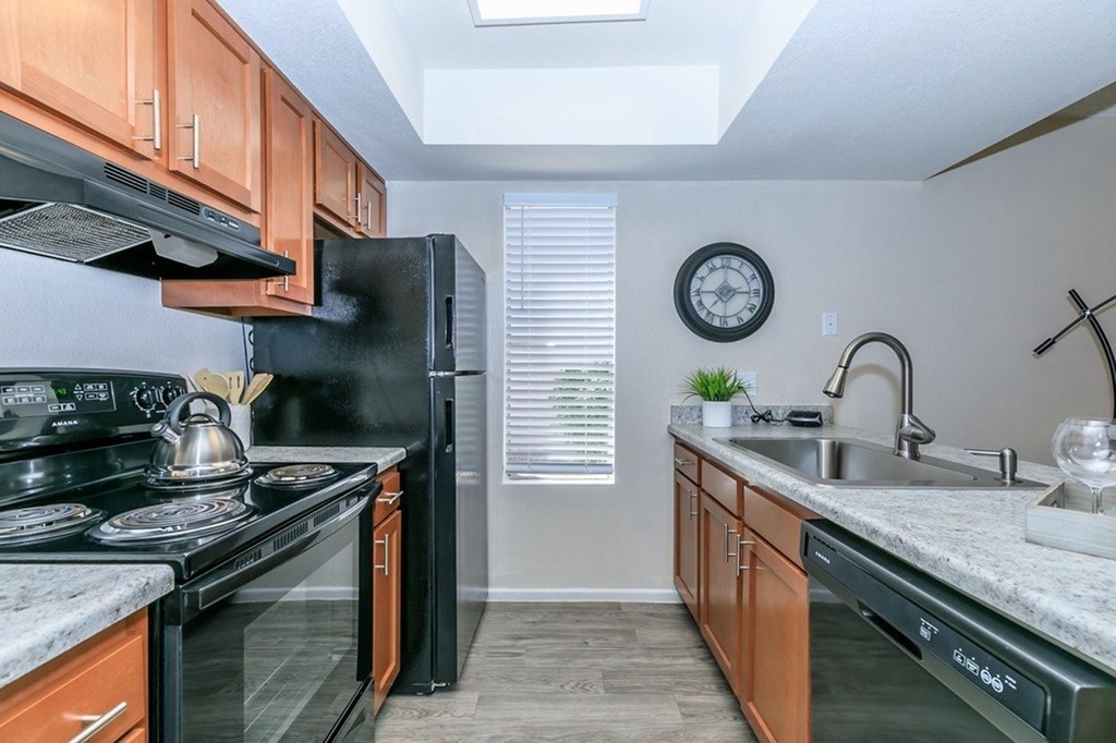 A kitchen with black appliances and wooden cabinets.