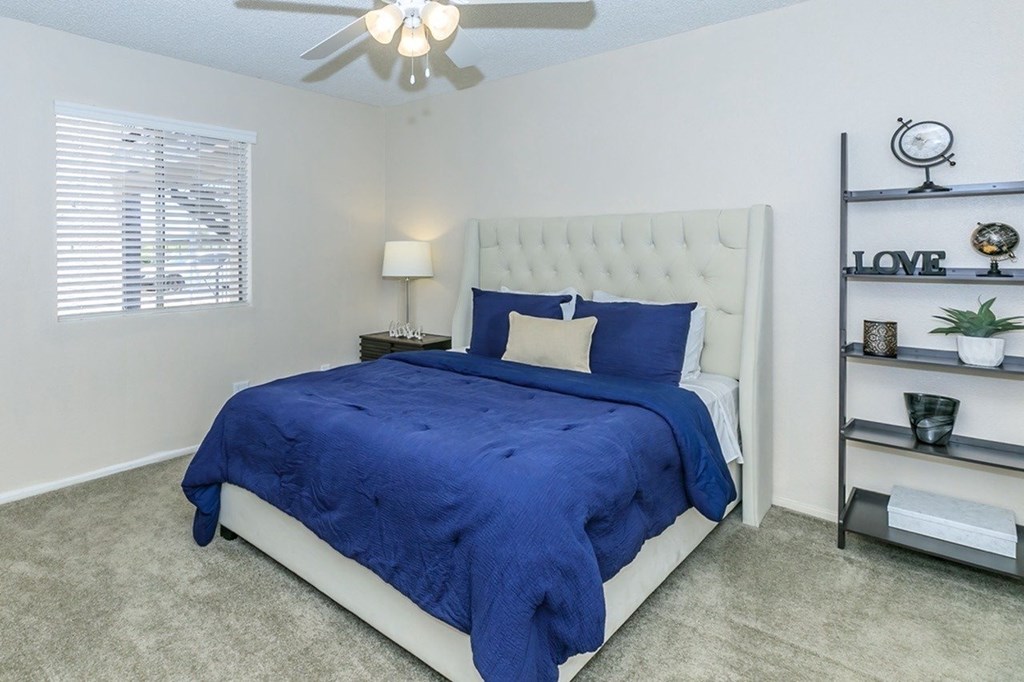 A bedroom with a bed covered in a blue comforter and a white headboard.
