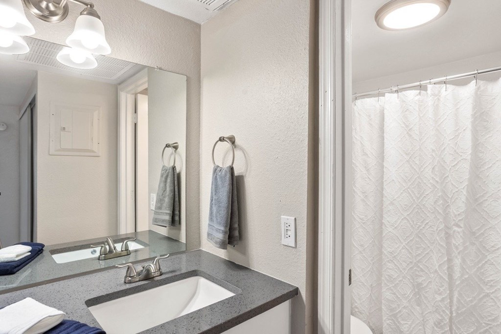 A bathroom with a sink, mirror, and shower curtain.