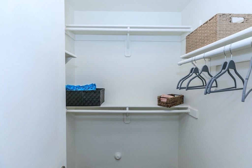 A white closet with a shelf and hangers.