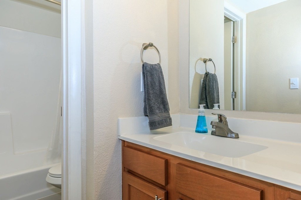 A bathroom with a white sink and a towel hanging on the towel ring.