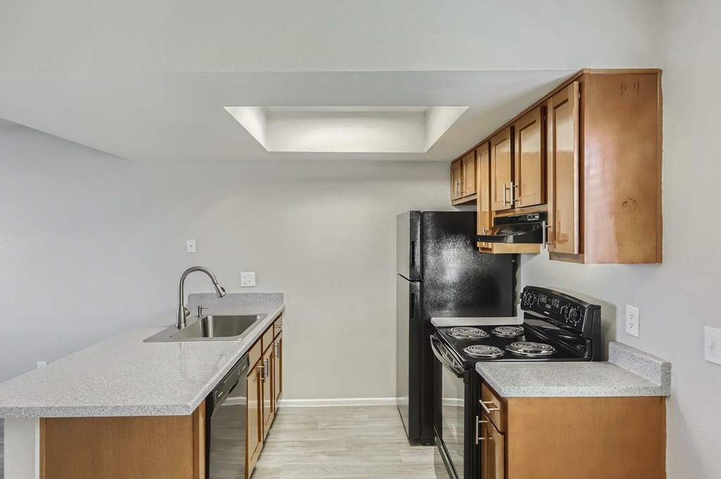 A kitchen with black appliances and wooden cabinets.