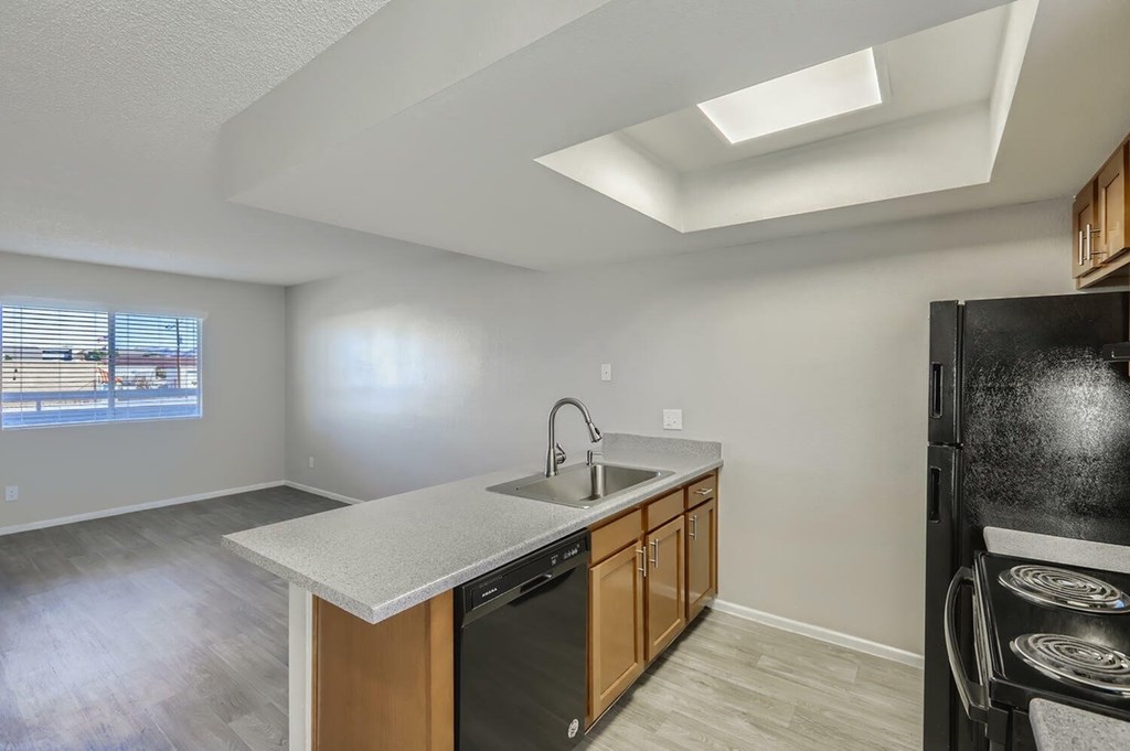 A kitchen with a black refrigerator and a window.