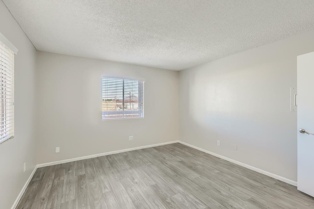 A room with a window and a wooden floor.