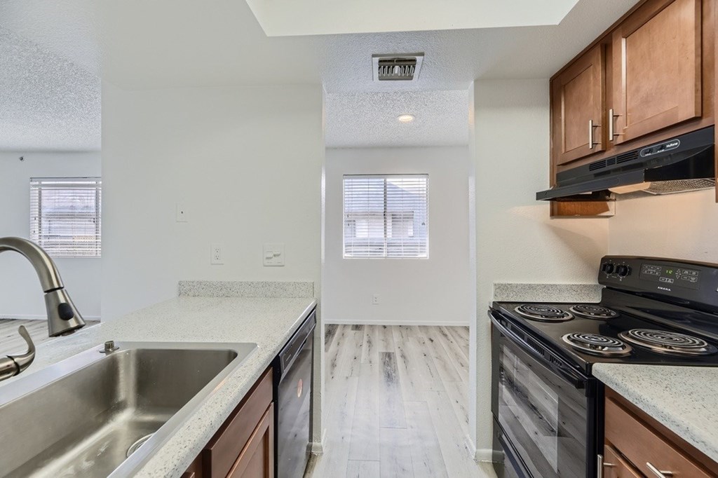 A kitchen with a stove, sink, and cabinets.