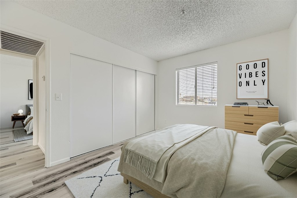 A bedroom with a bed, nightstand, and a poster on the wall.