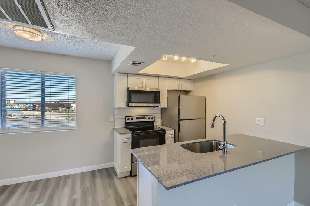 A kitchen with a sink, stove, and refrigerator.
