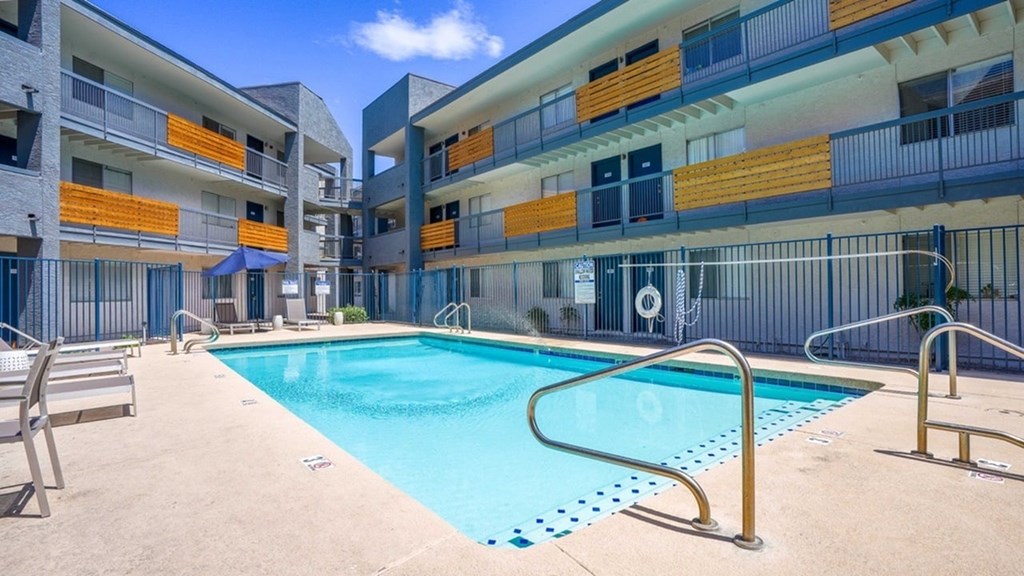 A swimming pool in front of a multi-story apartment building.