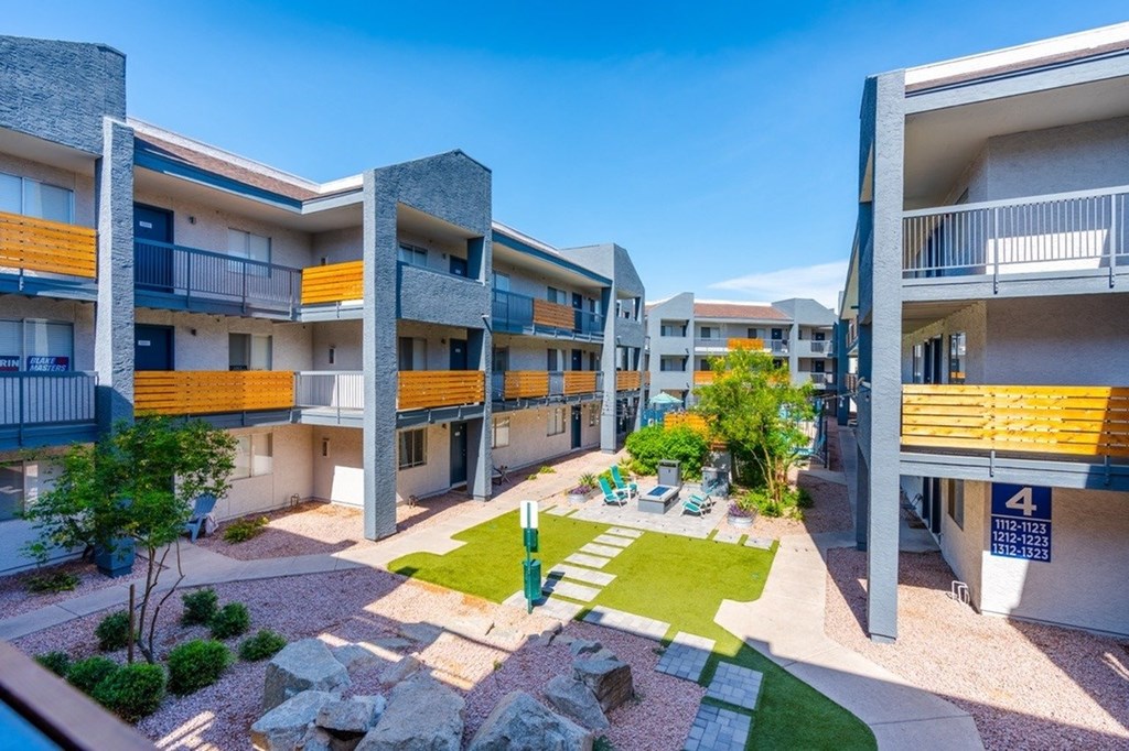 Apartment complex with balconies and a small garden area.