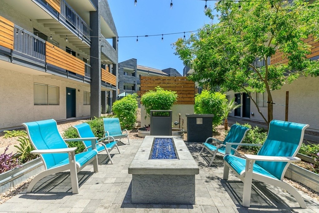 A patio with blue chairs and a fountain in the middle.