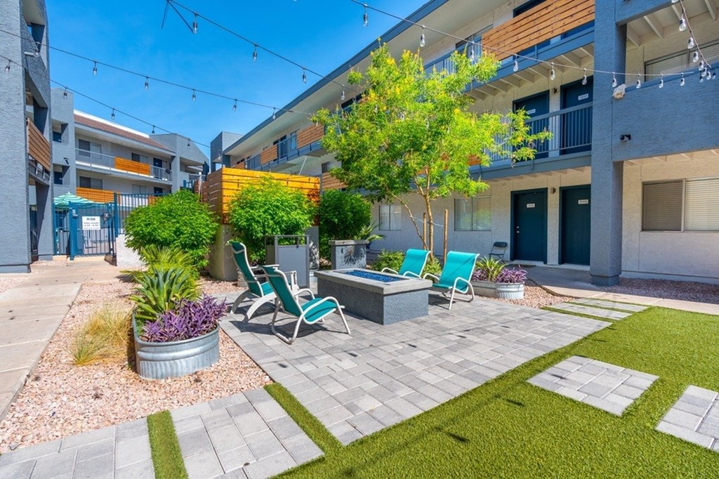 A patio area with a table and chairs surrounded by a grassy area and a building in the background.