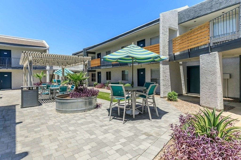 A patio with a table and chairs is surrounded by buildings.