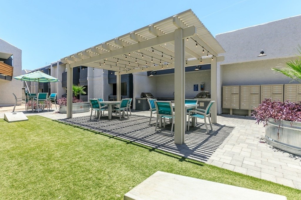 A patio with a white pergola and green chairs.