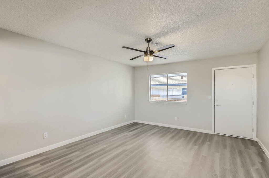 A room with a ceiling fan and a window with blinds.